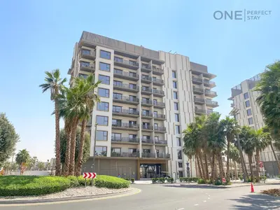 a large white building with palm trees in front of it at Modern Cozy Studio in Dubai