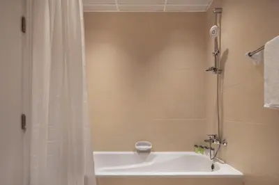 a bathroom with a bath tub with a shower curtain at Studio Nova at Dubai Sports City in Dubai