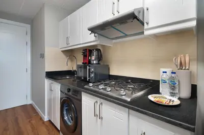 a kitchen with white cabinets and a stove top oven at Studio Nova at Dubai Sports City in Dubai