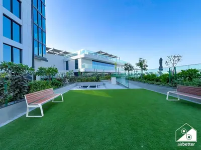 a building with two benches and a grass yard at Stunning 2-Bed Home in Sobha Creek Vistas in Dubai