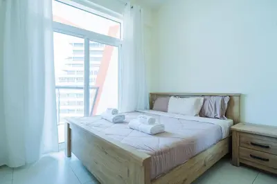 a bed in a room with a large window at 2BR Spacious Pearl with Stunning City Views - Holiday Boulevard in Dubai