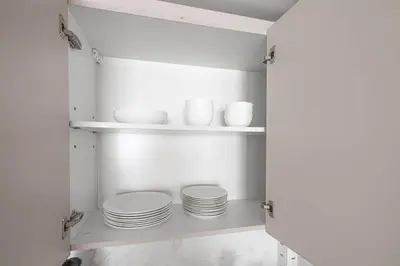 a kitchen with white plates and bowls on shelves at 41st-Floor 2BR with World's Highest Running Track in Dubai