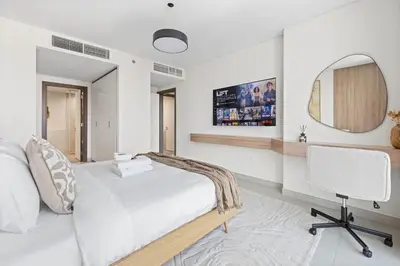 a bedroom with a bed and a desk and a mirror at 41st-Floor 2BR with World's Highest Running Track in Dubai
