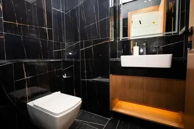 a black tiled bathroom with a toilet and a sink at Onyx 1BR with Stunning City Views in Dubai