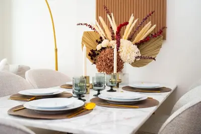 a white table with a vase of flowers on it at Onyx 1BR with Stunning City Views in Dubai