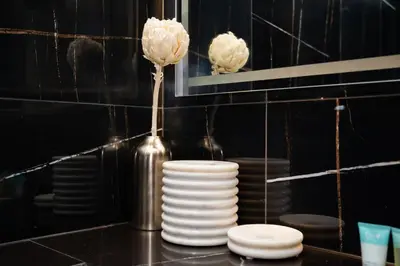 a stack of white plates and a vase with a flower at Onyx 1BR with Stunning City Views in Dubai