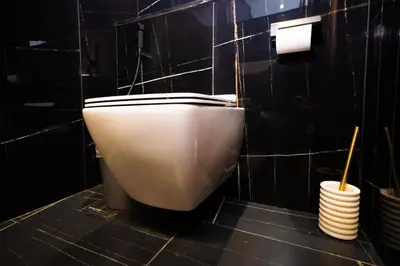 a white toilet in a black tiled bathroom at Luxury 1BR on High Floor JVC in Dubai