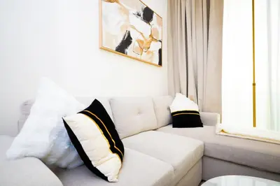 a white couch with black and white pillows in a living room at Elegant 1BR with High Rise JVC in Dubai