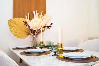 a dining room table with plates and a vase of flowers at Elegant 1BR with High Rise JVC in Dubai