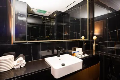 a black tiled bathroom with a sink and a mirror at Elegant 1BR with High Rise JVC in Dubai