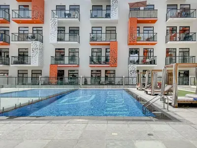 an apartment with a swimming pool in front of a building at Bright and Spacious 1 Bed Prime JVC Location in Dubai