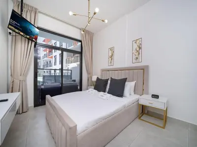a white bedroom with a large bed and a window at Bright and Spacious 1 Bed Prime JVC Location in Dubai