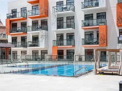 an apartment with a swimming pool in front of a building at Bright and Spacious 1 Bed Prime JVC Location in Dubai