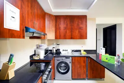 a kitchen with wooden cabinets and a washing machine at IDLE 1Bed Marina POOL &JBR BEACH in Dubai