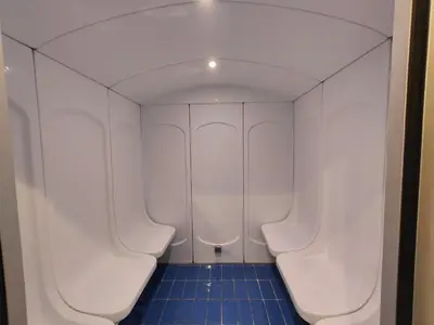 a bathroom with white urinals and a blue tile floor at Modern Studio with free Netflix - Close to Metro in Dubai