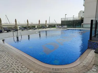 a large swimming pool with blue water in a building at Modern Studio with free Netflix - Close to Metro in Dubai