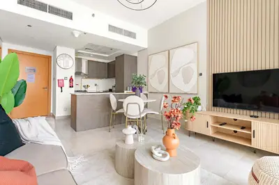 a living room with a television and a kitchen at Silkhaus 1BDR Holiday Stay at Pantheon Elysee in JVC in Dubai