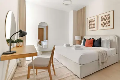 a white bedroom with a bed and a desk at Silkhaus 1BDR Holiday Stay at Pantheon Elysee in JVC in Dubai