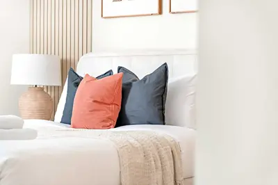 a white bed with a bunch of pillows on it at Silkhaus 1BDR Holiday Stay at Pantheon Elysee in JVC in Dubai