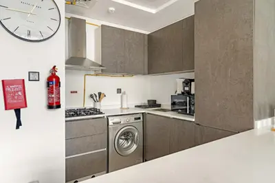 a kitchen with a washing machine and a clock on the wall at Silkhaus 1BDR Holiday Stay at Pantheon Elysee in JVC in Dubai