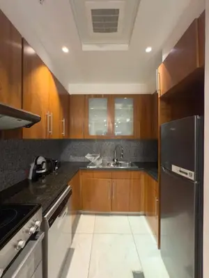 a kitchen with wooden cabinets and a stainless steel refrigerator at Nasma Luxury stays - Executive stay in the Heart of Dubai Financial Hub in Dubai