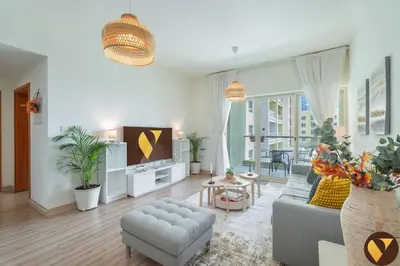 a living room with a couch and a tv at Vogue The Greens Al Alka near Mall of the Emirates, One Bedroom Apartment with Balcony and Vibrant community View, Access to all Amenities in Dubai