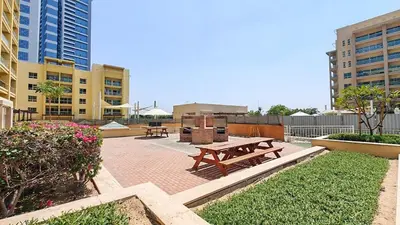 a patio with a picnic table and some buildings at Vogue The Greens Al Alka near Mall of the Emirates, One Bedroom Apartment with Balcony and Vibrant community View, Access to all Amenities in Dubai