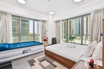 a bedroom with a bed and a large window at Stylish 2BR with Pool, Gym, Sauna & Kid's Playground in Dubai