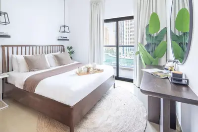 a bedroom with a bed with a table and a window at Frank Porter - Time Place Tower in Dubai
