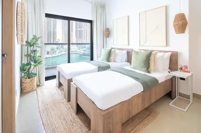 two beds in a room with a window at Frank Porter - Time Place Tower in Dubai