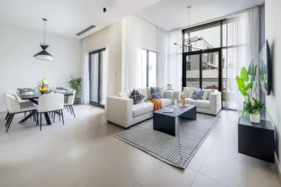 a living room with white furniture and a dining room at Frank Porter - Murooj Al Furjan West in Dubai