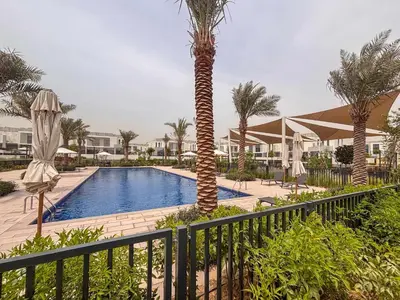 a resort pool with a palm tree and a fence at Frank Porter - Murooj Al Furjan West in Dubai
