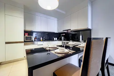 a kitchen with white cabinets and a table and chairs at Modern 1-Bedroom in Address Marina, City View - 20AB01 in Dubai