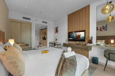 a bedroom with a white bed and a television at Luxury Palm Studio, Rooftop Infinity Pool, Beach Access in Dubai