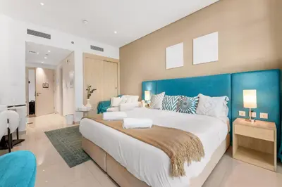 a large bedroom with a large bed with a blue headboard at Luxury Palm Studio, Rooftop Infinity Pool, Beach Access in Dubai