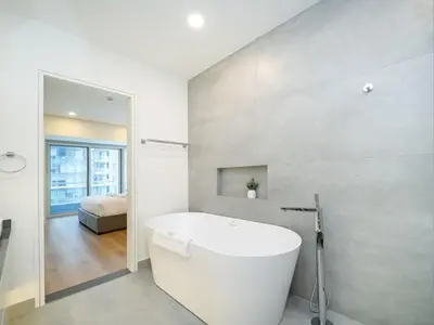 a bathroom with a white tub and a bedroom at Stunning 2-Bedroom Duplex in Dubai Marina in Dubai