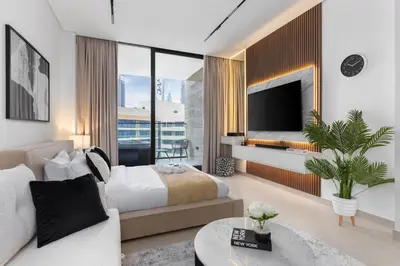 a living room with a bed and a tv at Waves - Luxe Studio with Jacuzzi & City Views in Dubai