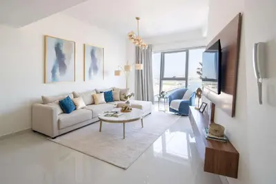a white living room with a couch and a tv at Frank Porter - Damac Heights in Dubai