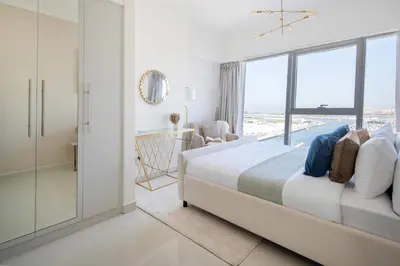 a white bedroom with a large bed and a window at Frank Porter - Damac Heights in Dubai