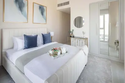 a bedroom with a large white bed with blue pillows at Frank Porter - Damac Heights in Dubai
