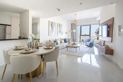 a dining room and living room with a table and chairs at Frank Porter - Damac Heights in Dubai