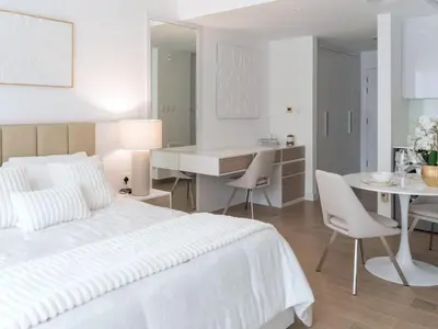 a white bedroom with a white bed and a table and chairs at Luxury Furnished, Brand New in Dubai