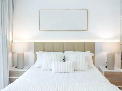 a bedroom with a white bed with two lamps at Luxury Furnished, Brand New in Dubai