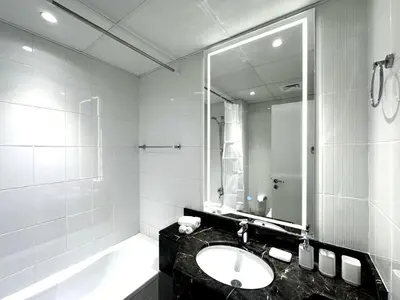 a bathroom with a sink and a tub and a mirror at Luxury Furnished, Brand New in Dubai