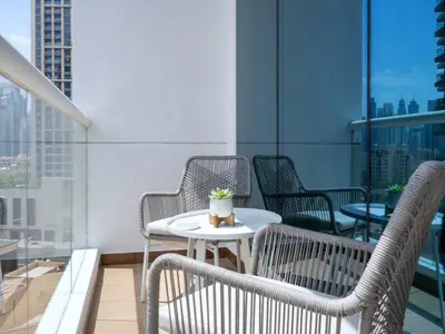a patio with chairs and a table on a balcony at Luxury Furnished, Brand New in Dubai