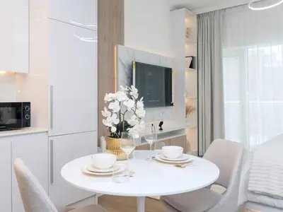a white table with a vase of flowers on it at Luxury Furnished, Brand New in Dubai