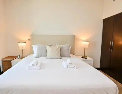 a bedroom with a large white bed with towels on it at The Lofts East Unique 1BR Boulevard Views close to Dubai Mall in Dubai