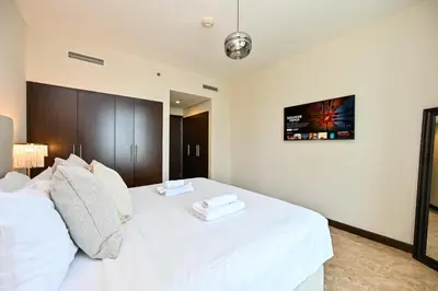 a bedroom with a white bed with a tv on the wall at The Lofts East Unique 1BR Boulevard Views close to Dubai Mall in Dubai