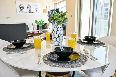 a white dining room table with glasses of orange juice at The Lofts East Unique 1BR Boulevard Views close to Dubai Mall in Dubai