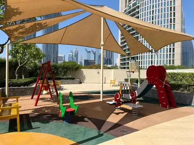 a playground with a large umbrella and play equipment at The Lofts East Unique 1BR Boulevard Views close to Dubai Mall in Dubai